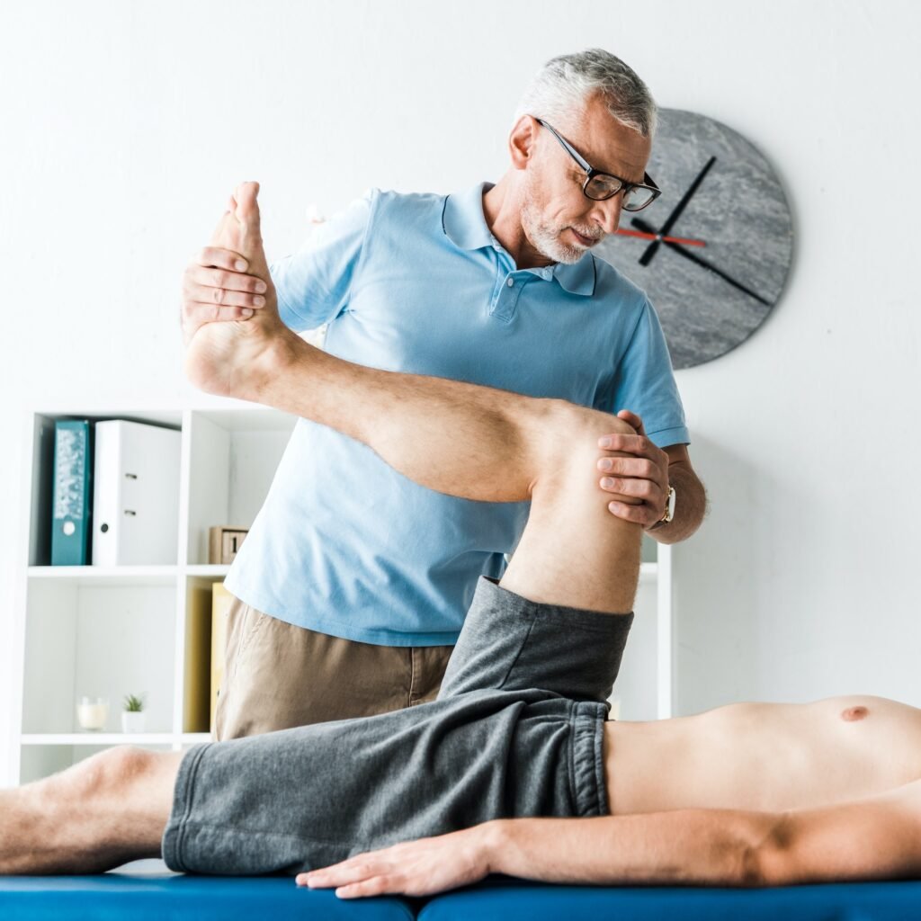 cropped view of patient lying on massage table and working out near doctor in glasses